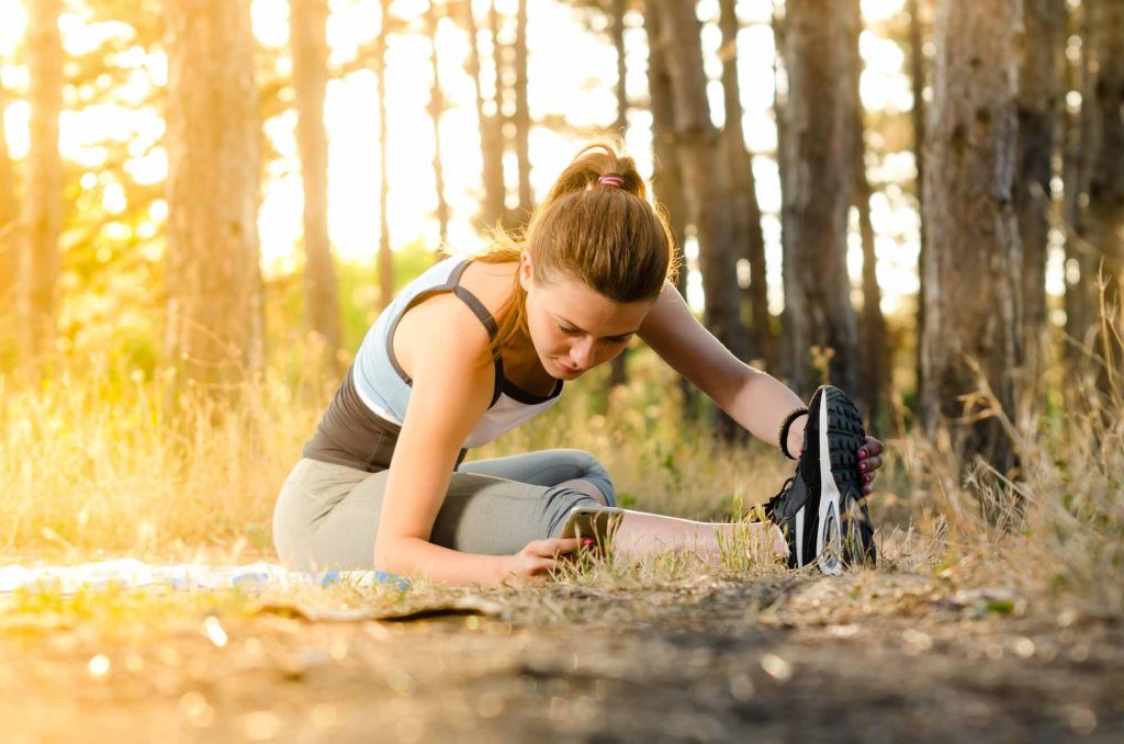 woman stretching outside while doing her morning workout.