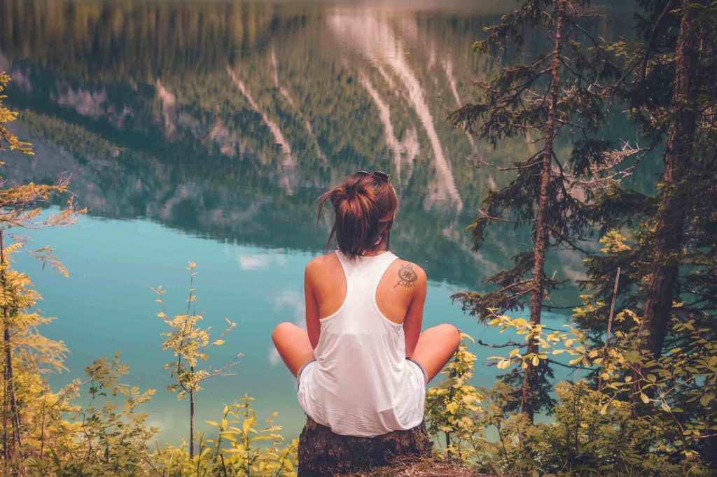 young woman in nature meditating wearing white