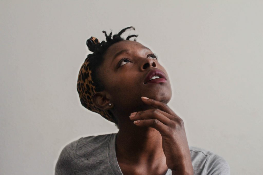 Girl looking upward with her hand on her chin thinking